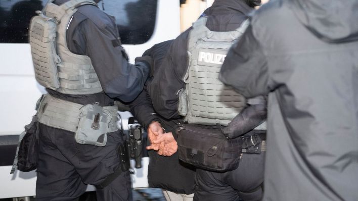 Symbolbild: Polizisten führen einen Mann aus einem Wohnhaus. (Quelle: dpa/Paul Zinken)