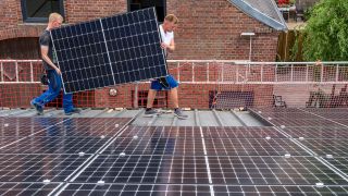 Symbolbild: Montage von Solarmodulen auf das Dach eines Gebäudes. (Quelle: dpa/J. Tack)
