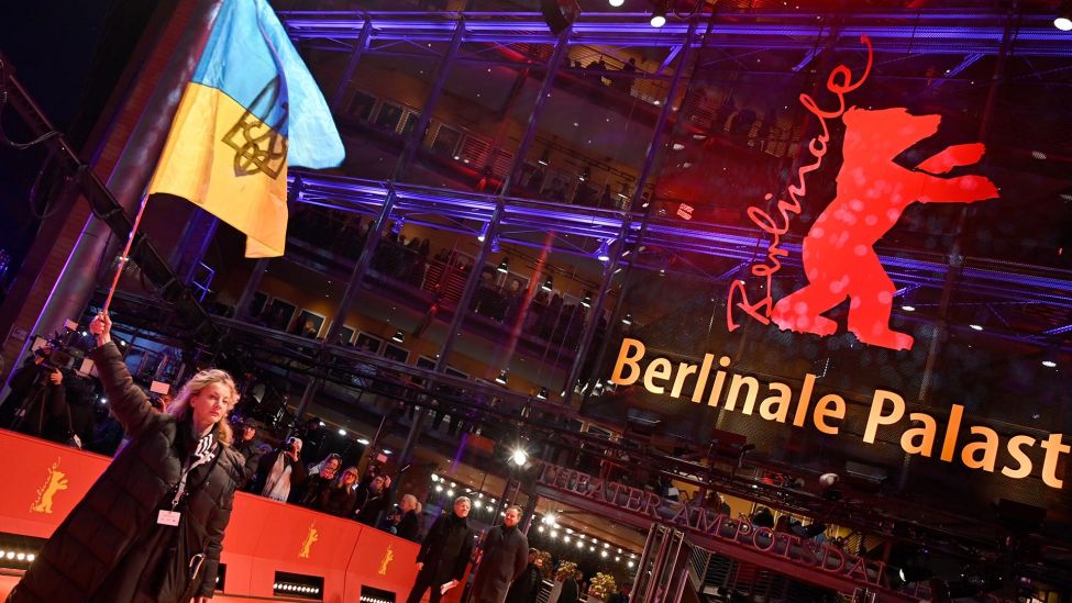 Diana Berg, Schauspielerin, schwenkt eine ukrainische Flagge auf dem roten Teppich zur Preisverleihung der Berlinale. (Quelle: dpa/F. Sommer)