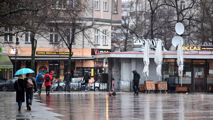 Passanten gehen bei Regen über den Winterfeldtplatz im Ortsteil Schöneberg des Berliner Bezirks Tempelhof-Schöneberg. (Quelle: Soeren Stache/dpa)