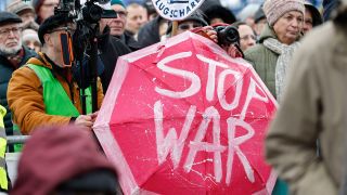 Teilnehmer:innen der Demonstration vor dem Brandenburger Tor mit einem "Stop War"-Regenschirm (Bild: imago images/Jean MW)