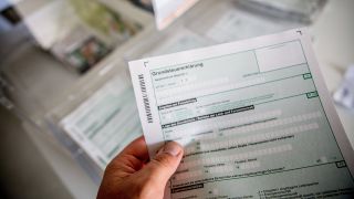 Symbolbild: Eine Person besorgt sich den Antrag in Papierform für die Grundsteuer (Quelle: IMAGO/K.Schmitt)