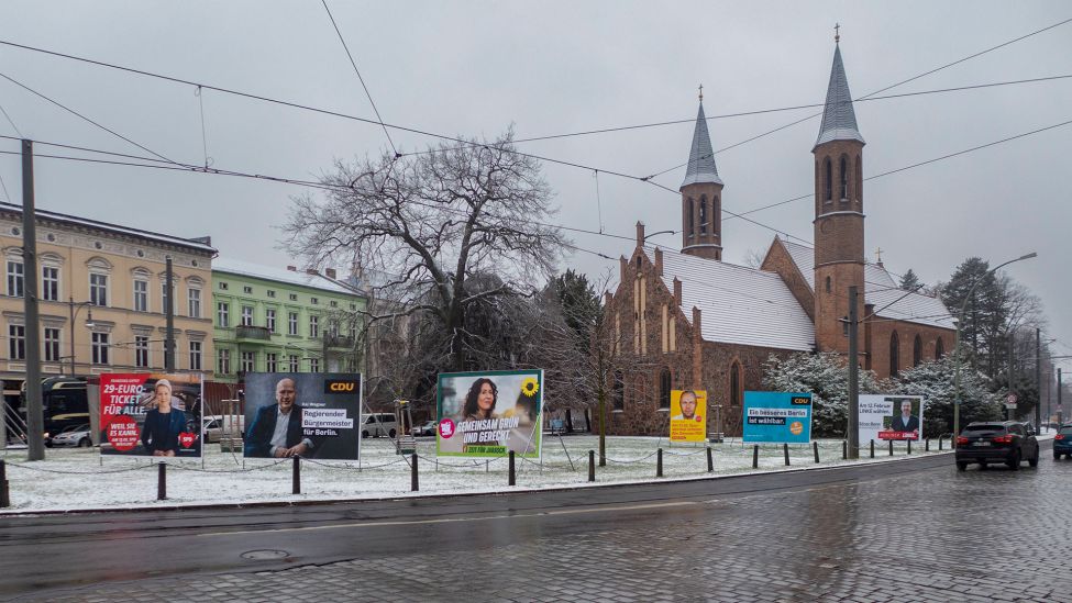 Schnee liegt rund um die Plakate zur Wahlwiederholung in Berlin Pankow, vor der Kirche an der Breite Straße. (Quelle: imago images/R. Zöllner)