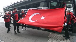 Teile der Volleyballmannschaft aus Ankara halten bei ihrer Ankunft in Berlin eine Türkische Flagge hoch (rbb)