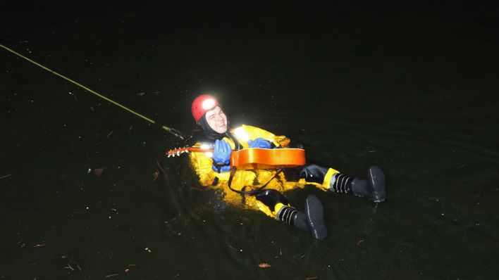 Ein Feuerwehrmann tut so als würde er auf der geretteten Gitarre im Wasser spielen.(Quelle:Morris Pudwell)