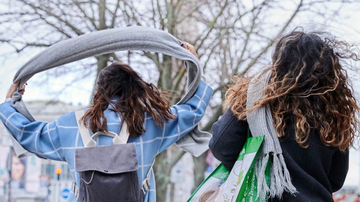 Archivbild: Zwei Frauen gehen am 17.02.2022 mit wehendem Haar und fliegenden Schals Richtung Alexanderplatz. (Quelle: dpa/Annette Riedl)