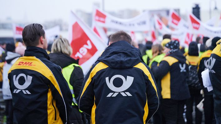 Das Post-Logo ist am 06.02.2023 auf den Jacken der Demonstranten der Deutschen Post zu sehen, die vor der Ver.di Bundeszentrale auf der Schillingbrücke streiken. (Quelle: dpa-Bildfunk/Annette Riedl)
