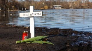 Nach dem Fund zweier Leichen im Weißen See sind am 28.02.2023 an dem Fundort ein Kreuz, Blumen und eine Kerze zu sehen. (Quelle: dpa/Jörg Carstensen)