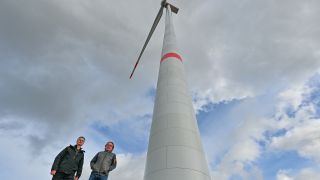 Axel Kalhorn (l), Chef des Trägervereins der Freien Schule Angermünde und Jan Teut, Unternehmer und Investor, stehen am 06.03.2023 vor einer neuen Windenergieanlage. (Quelle: dpa/Patrick Pleul)