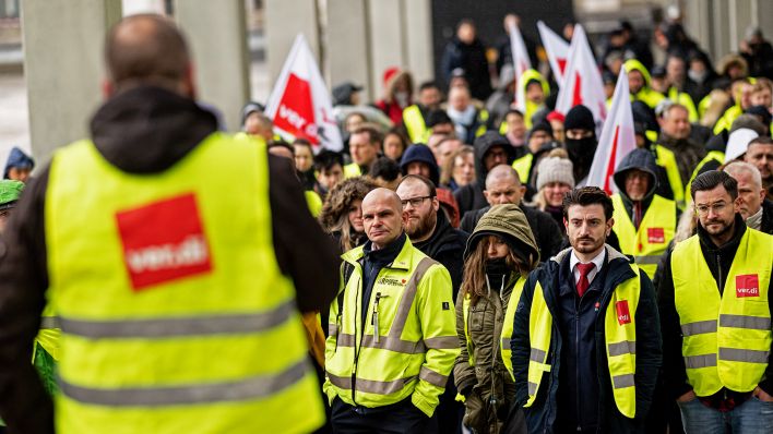 Streikende stehen am13.03.2023 während dem Warnstreiks von Verdi vor dem BER-Terminal auf dem Willy-Brandt-Platz zu einer Kundgebung zusammen.(Quelle:dpa/F.Sommer)
