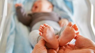 Symbolbild:Hände der Mutter halten die kleinen Füße von Baby.(Quelle:dpa/R.Kneschke)
