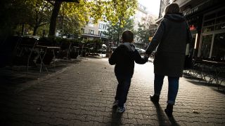 Symbolbild: Eine Frau geht mit einem Kind an der Hand in Berlin durch die Stadt (Bild: dpa/Christin Klose)