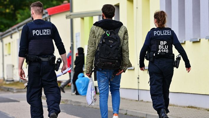 Symbolbild:Zwei Beamte der Bundespolizei begleiten einen Flüchtling auf dem Gelände der Zentralen Erstaufnahmeeinrichtung für Asylbewerber (ZABH) des Landes Brandenburg.(Quelle:dpa/P.Pleul)