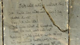 Blick auf eine Originalinschrift auf einer Liege des ehemaligen Jugendwerkhofes im sächsischen Torgau (Quelle: DPA/Peter Endig)