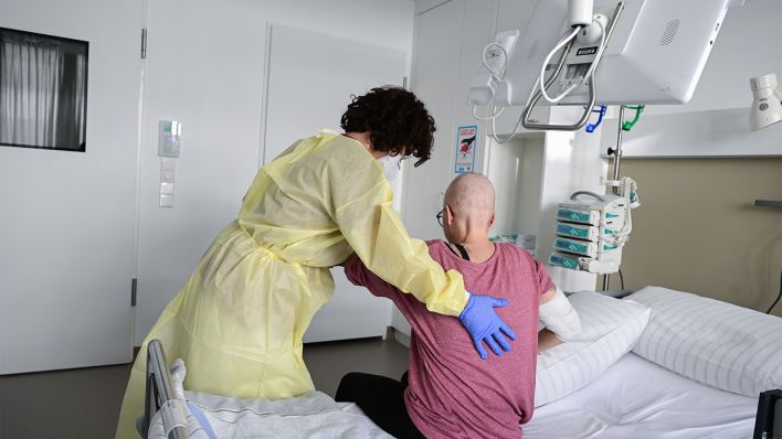 Eine Pflegerin begleitet eine Patientin im Krankenhaus (Bild: dpa/Bernd Weißbrod)