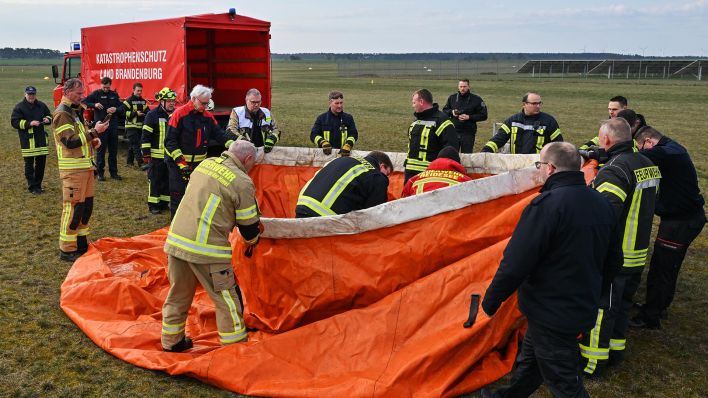 Einsatzkräfte der Feuerwehr errichten bei einer Übung auf dem Flugplatz Müncheberg-Eggersdorf am 30.03.2023 eine mobile Wasserentnahmestelle.(Quelle:dpa/P.Pleul)
