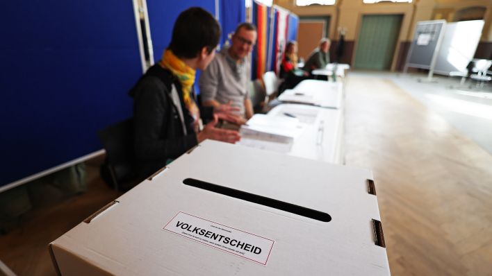Wahlhelfer sitzen vor einer Wahlurne in einem Wahllokal im Bildungs- und Kulturzentrum Peter Edel in Berlin-Weissensee.(Quelle:dpa/J.Carstensen)