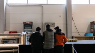 Drei junge Männer holen sich im Kantinenbereich einer Notunterkunft jeweils einen Tee. (Quelle: dpa/Philipp von Ditfurth)