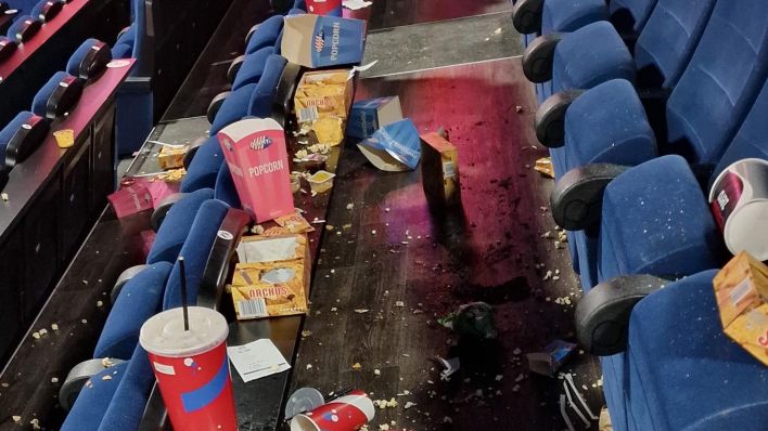 Symbolbild: Popcorn und Getränke liegen in einer noch nicht gereinigten Reihe eines Kinosaals verstreut. (Quelle: dpa)