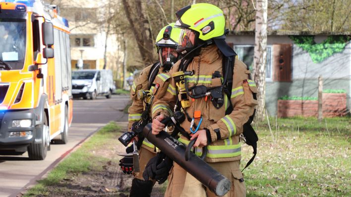 Feuerwehrleute gehen unter Atemschutz zu einem Altenheim in Hohenschönhausen. (Quelle: dpa/Paul Zinken)