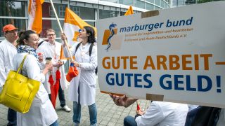 Demonstraten halten ein Plakat mit der Aufschrift "Gute Arbeit - Gutes Geld!" (Quelle: dpa/Paul Zinken)
