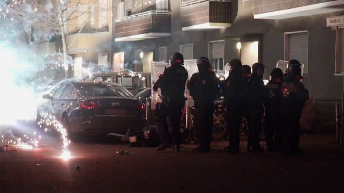 Archivbild: Polizeibeamte stehen hinter explodierendem Feuerwerk. (Quelle: dpa/TNN)