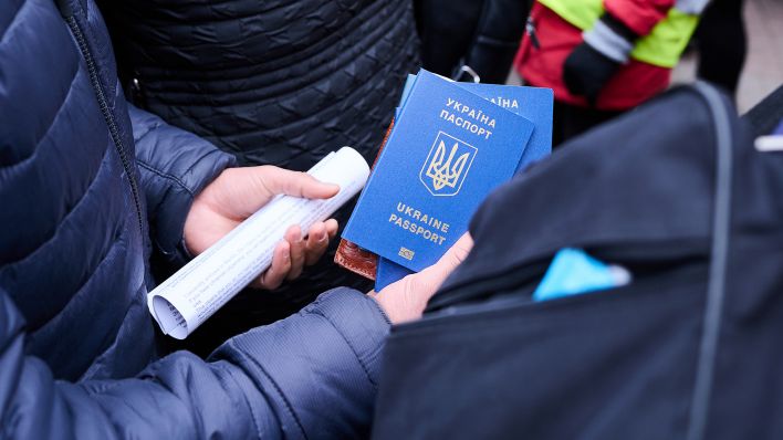 Symbolbild: Ein Mann hält Ukrainische Pässe in den Händen. (Quelle: dpa/A. Riedl)