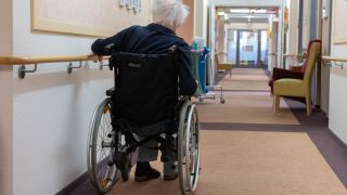 Archivbild: Ein Senior fährt mit seinem Rollstuhl in einem Schöneberger Pflegeheim einen Flur entlang. (Quelle: dpa/P. Zinken)