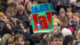 Archivbild: Ein Teilnehmer der Demonstration von Fridays for Future hält ein Plakat mit der Aufschrift "26.03. Berlin 2030 klimaneutral. Ja zum Volksentscheid" hoch. (Quelle: dpa/M. Skolimowska)