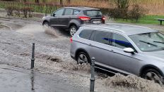 Autos fahren durch eine von Regen überflutete Straße. (Quelle: dpa/C. Dettlaff)
