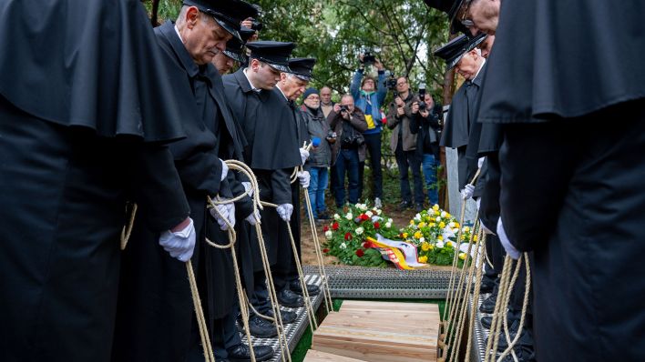 Gebeinekisten mit menschlichen Knochen werden nach der Trauerfeier am 23.03.2023 in ein Grab auf dem Waldfriedhof Dahlem hinabgelassen.(Quelle:dpa/M.Skolimowska)