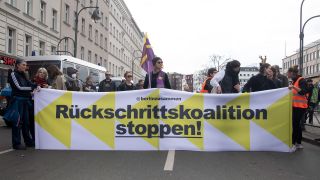 Teilnehmer halten ein Banner mit der Aufschrift «Rückschrittskoalition stoppen!» während einer Demonstration gegen eine CDU-SPD-Regierung in Berlin. (Quelle: dpa/Paul Zinken)