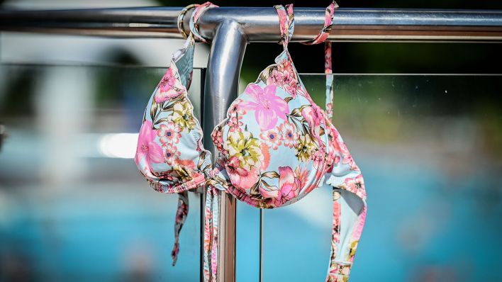 Symbolbild:Ein Bikini hängt über einem Geländer im Freibad.(Quelle:imago images/K.Kokoska)