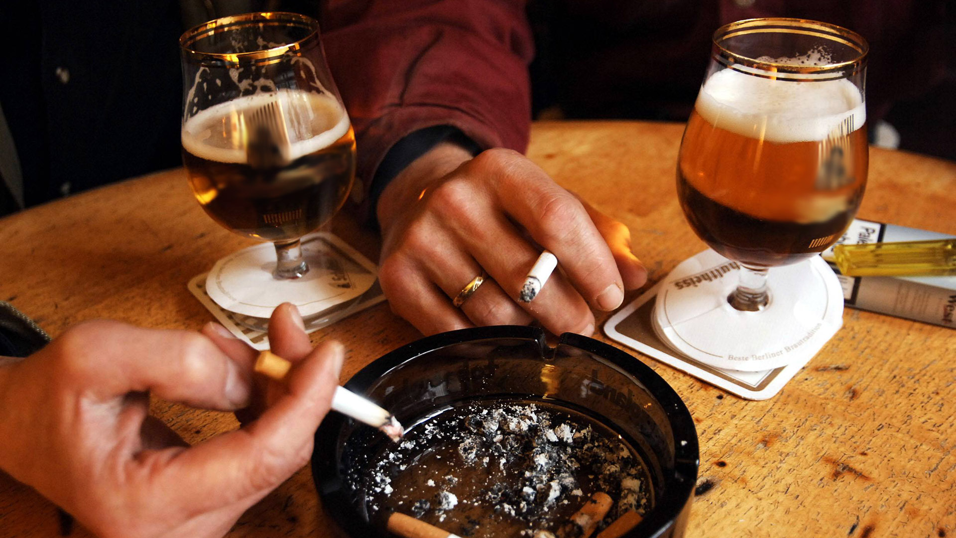 Symbolbild:Kneipenbesucher trinken Bier und rauchen Zigaretten.(Quelle:imago images/S.Lambert)