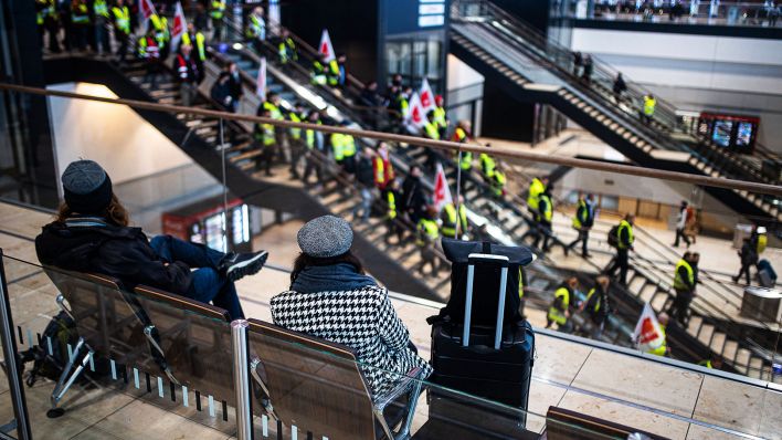 Ein Warnstreik der verdi legt am 13. März 2023 den Flughafen Berlin Brandenburg lahm. Reisende beobachten die Streikenden im Terminal. Warnstreik am BER.(Quelle:imago images/R.Keuenhof)