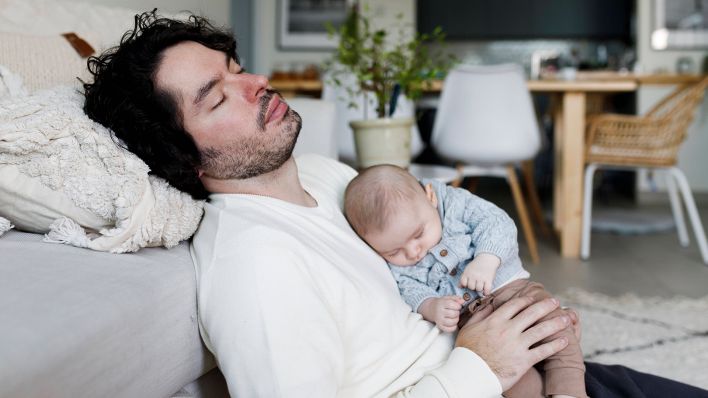 Symbolbild: Ein müder Vater ist eingeschlafen (Quelle: IMAGO/Tanya Yatsenko)