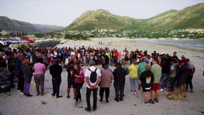 Zahlreiche Menschen versammeln sich am Strand von Kapstadt, um an den Vermissten aus Döbern zu gedenken (Quelle: rbb)