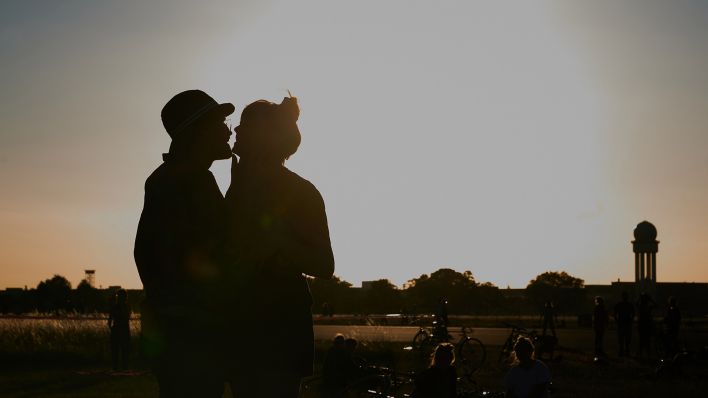 Symbolbild: Ein Pärchen küsst sich am 23.06.2020 bei Abendstimmung auf dem Tempelhofer Feld. (Quelle: dpa/Annete Riedl)