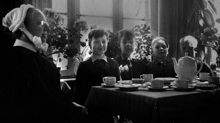 Archivbild:"Verschickungskinder" sitzen 1954 mit einer Betreuerin an einem gedeckten Kaffeetisch.(Quelle:dpa/C.Sandig)