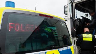 Symbolbid: Ein Polizist kontrolliert einen LKW-Fahrer auf einem Rastplatz an einer Autobahn. (Quelle: dpa/Demy Becker)