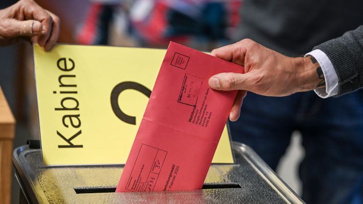 Zum Beginn der Briefwahl für die Wiederholungswahlen am 12. Februar wählt ein Mann im Rathaus Zehlendorf und steckt seine Stimmzettel in einem Briefumschlag für die Briefwahl in die Wahlurne. (Quelle: dpa/Jens Kalaene)