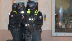 Bewaffnete Einsatzkräfte der Polizei stehen vor einem Haus am Park am Weißen See im Stadtteil Weißensee. (Quelle: dpa/Paul Zinken)