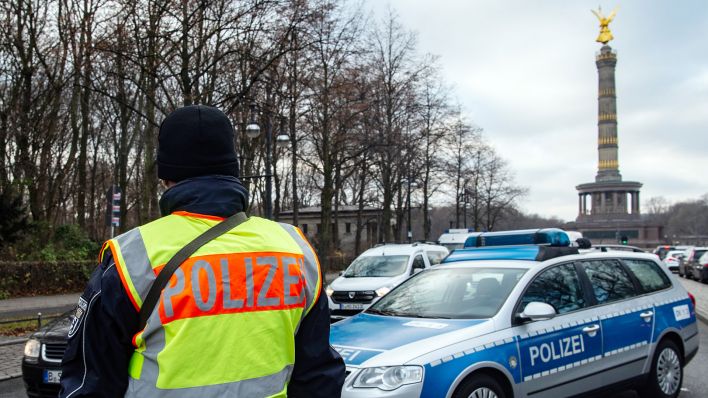 Symbolbild: Polizisten kontrollieren auf einer Straße nahe dem Großen Stern einige Autos. (Quelle: dpa/P. Zinken)