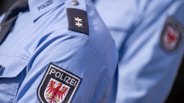 Symbolbild: Das Logo der Brandenburger Polizei mit rotem Adler und Schriftzug auf der Uniform eines Polizeibeamten. (Quelle: dpa/M. Skolimowska)