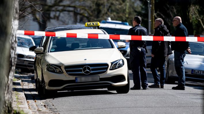 Mitarbeiter der Berliner Polizei steht vor einem Taxi in Berlin-Grunewald. Am Donnerstagmorgen gab in der Brahmsstraße es einen tätlichen Angriff auf den Fahrer des Taxis. (Quelle: dpa/Fabian Sommer)