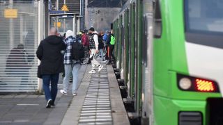 Passagiere neben einem Zug der Rhein-Ruhr-Bahn, Aufnahme aus 2022 (Quelle: picture alliance / Jens Niering)