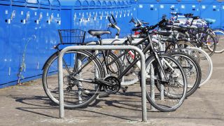 Symbolbild:Fahrräder stehen an Ständern vor einer Reihe blauer Fahrradboxen.(Quelle:imago images/T.Krueger)
