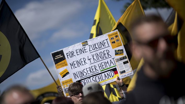 Symbolbild:Rechtsextreme Demonstrierende halten ein Schild mit der Aufschrift:"Für eine Zukunft meiner 4 Kinder in unserer Heimat Deutschland".(Quelle:imago images)