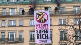 Mitglieder der Gruppe "Extinction Rebellion" protestieren am 13.04.2023 mit einem an der Fassade des Hotel Adlon in Berlin aufgehängten Transparent durch die Ausbeutung von Ressourcen durch aus ihrer Sicht "Superreiche" (Quelle: rbb / Höppner).