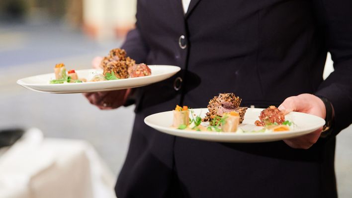 Beim Internationaler „L'Art de Vivre Wettbewerb“ für Servicekräfte in Restaurants und Hotels trägt eine Servicekraft Teller zu den Tischen der Gäste. (Quelle: dpa/Annette Riedl)